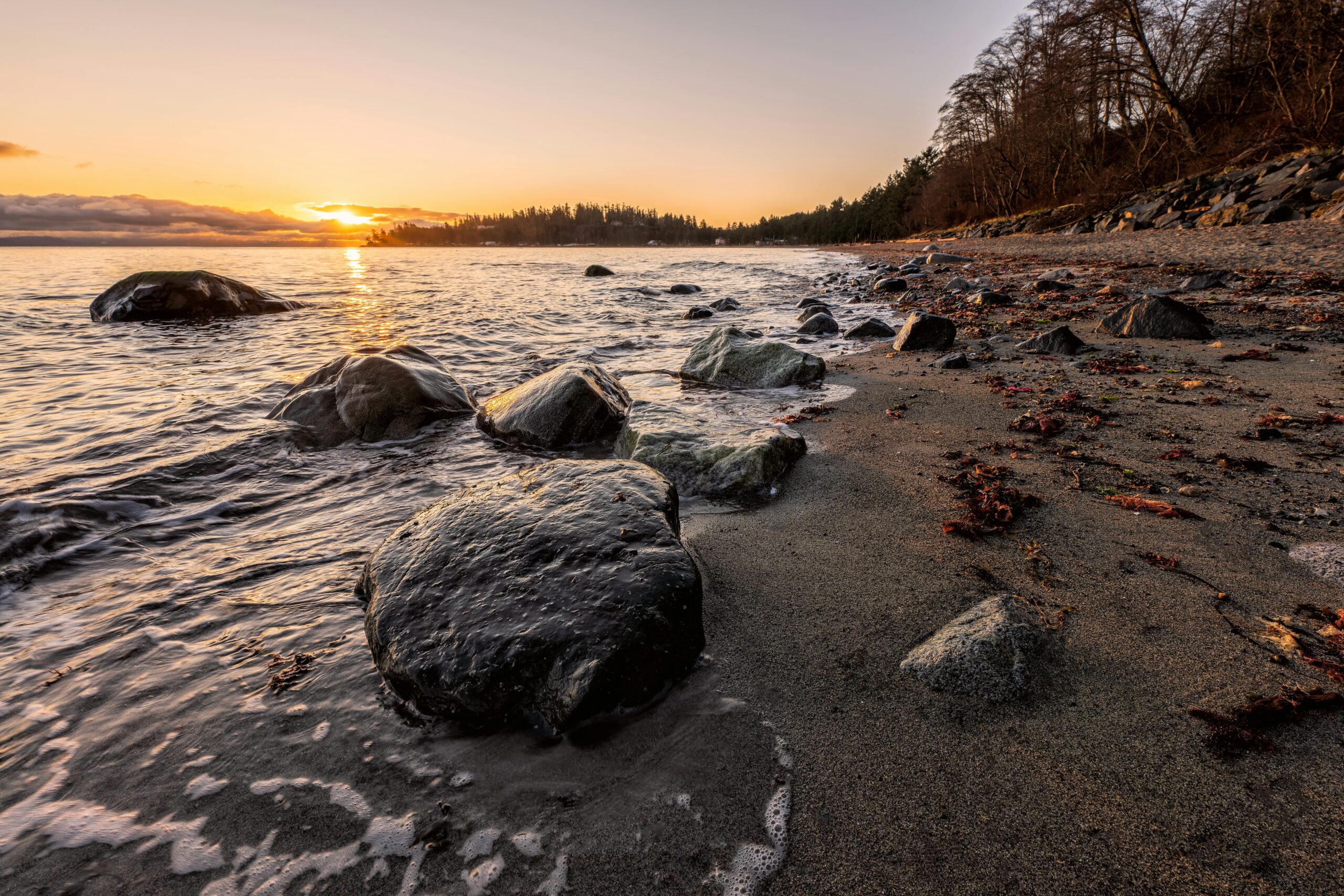 plage tranquille, coucher de soleil, rochers sur la plage, lumière dorée, nature sauvage, relaxation, sérénité, bord de mer, ambiance apaisante, contemplation